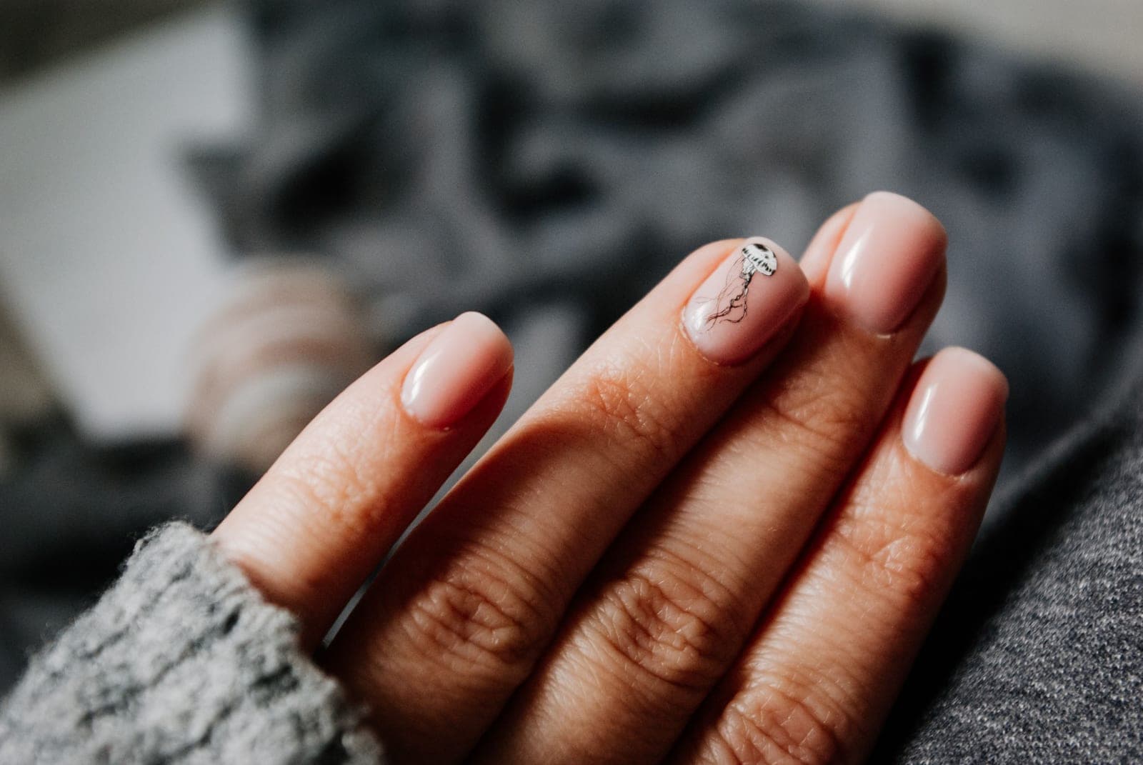 Someone painting gel polish onto their own nails at a table