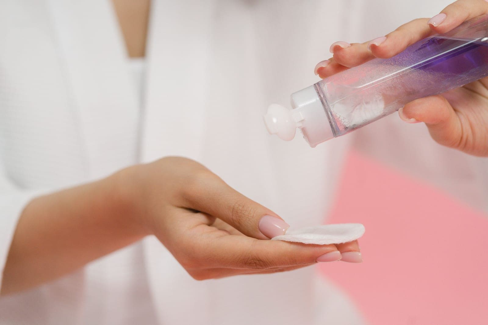 A nail polish remover bottle beside cotton pads