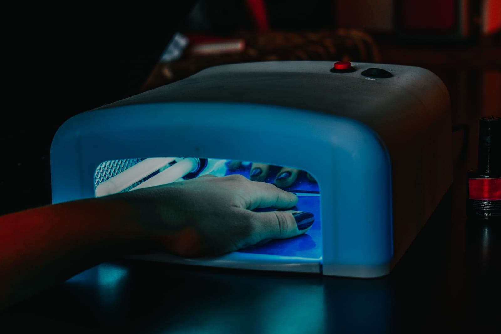 A UV/LED nail lamp on a table with a hand inside — a category photo, not this product